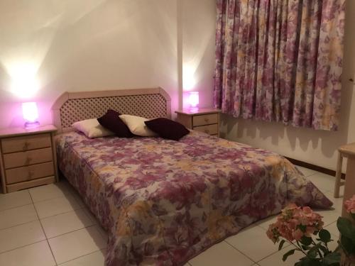 波尔蒂芒T1 - Praia da Rocha - com Vistas de Mar e Terraço的一间卧室配有一张带2个床头柜和2盏灯的床。