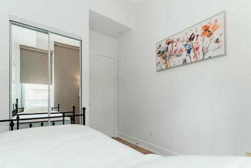 列治文山Cozy & Contemporary Suite - Easy Access to Everything的卧室配有白色的床和镜子