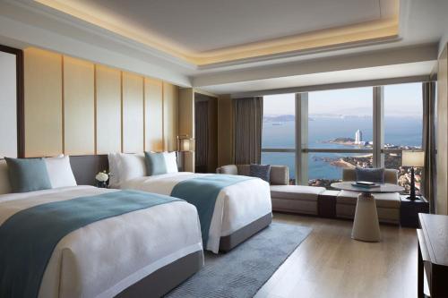 青岛青岛瑞吉酒店的酒店客房设有两张床和大窗户。