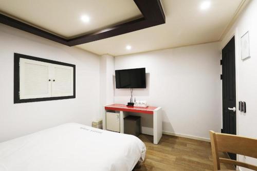 水原市Suwon Hotel Praha的一间卧室配有一张床和一张书桌及电视