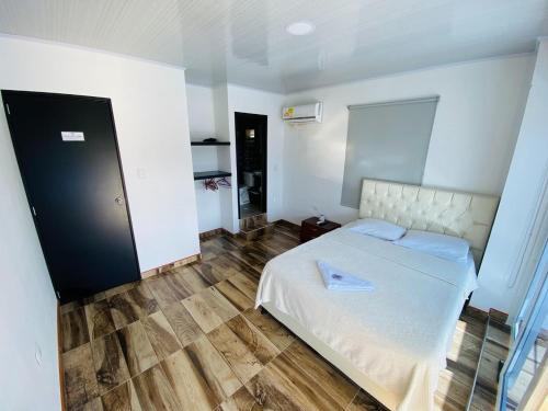 TauramenaHOTEL LA CASONA的卧室配有白色的床,铺有木地板
