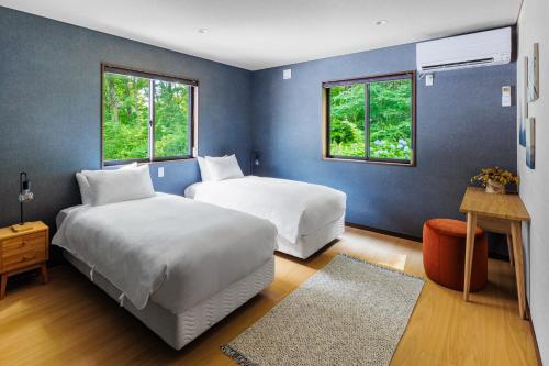 白马村MIZUHO CHALETS by Hakuba Hotel Group的配有两张床铺的蓝色墙壁和窗户