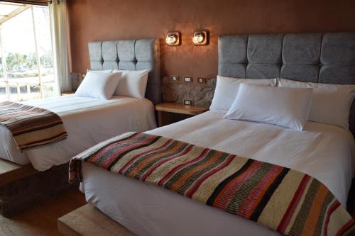 奥科苏尤Allpaluxe Peru Lodge的酒店客房设有两张床和窗户。
