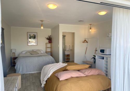 帕帕莫阿Pāpāmoa Beach Studio Oasis的一间带两张床的卧室和一间带微波炉的厨房