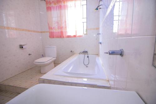 AtasomansoKiverly Guest House的带浴缸、卫生间和盥洗盆的浴室