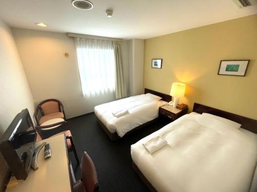 米子市米子微笑酒店的酒店客房配有两张床和一张书桌