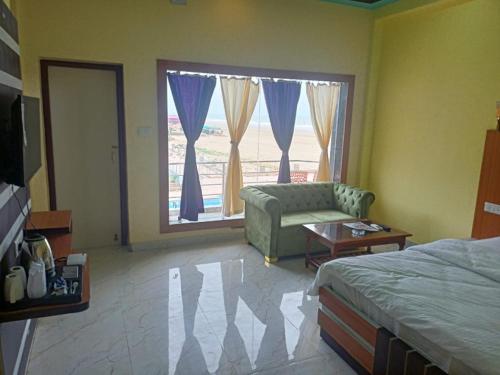 曼达莫尼ST Apple Beach Resort Mandarmani的一间卧室配有一张床、一张沙发和一个窗口