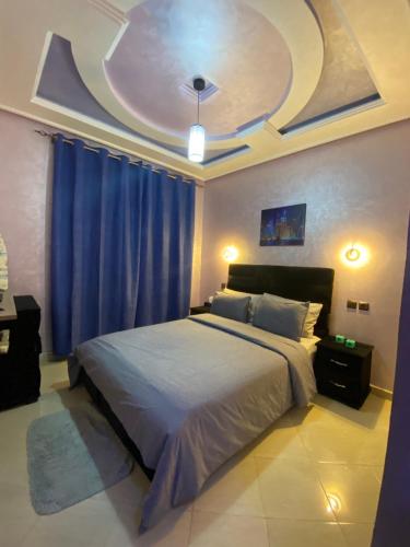 胡里卜盖khouribga的一间卧室配有一张带蓝色窗帘的大床