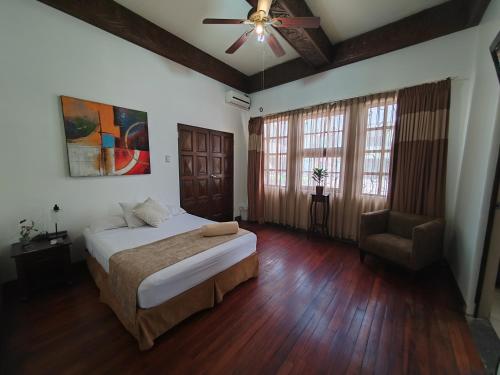 圣何塞卡萨克隆旅馆的卧室配有1张床、吊扇和1把椅子