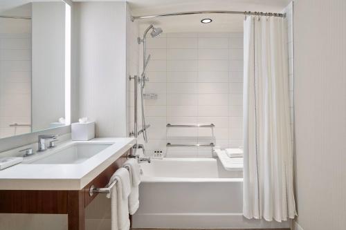 威斯敏斯特Delta Hotels by Marriott Denver Thornton的白色的浴室设有浴缸和水槽。