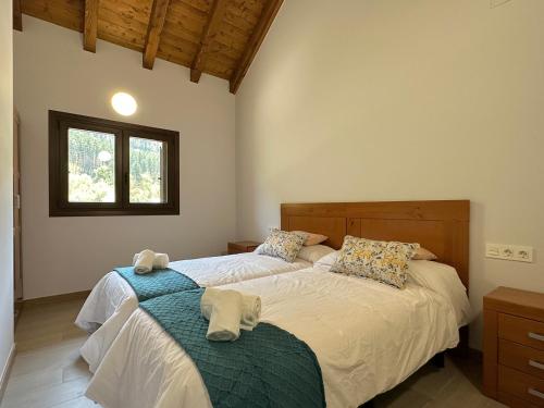 BurguiApartamentos Rurales AINARIAK的一间卧室设有两张床和窗户。
