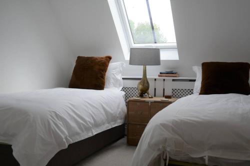 Middle BartonLuxury Barn near Soho Farmhouse的一间卧室配有两张床和床头灯。