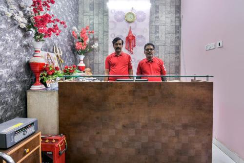 GulzārbāghOYO Flagship Rainbow Homestay的两个穿着红衬衫的人站在柜台后面