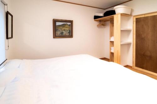 十和田Immaculate Private Family Cottage with Hot Spring的卧室配有白色的床和木制橱柜。