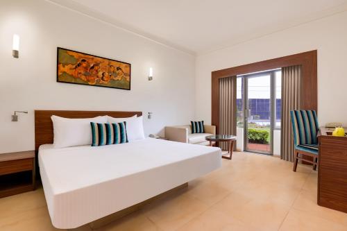 奥兰加巴德奥兰加巴德柠檬树酒店的卧室配有一张白色大床和一张书桌