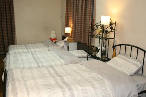 神户Private Inn Bambee的一间卧室配有两张带白色床单的床