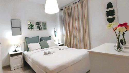 拉拉古纳Confortable vivienda en La Laguna a 5 MIN tranvía的白色卧室配有一张带鲜花的大床