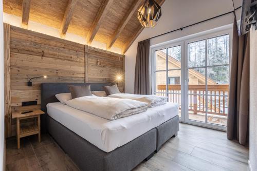 玛丽亚普法尔AlpiNest Feriendorf Lungau的一间卧室设有一张大床和一个大窗户