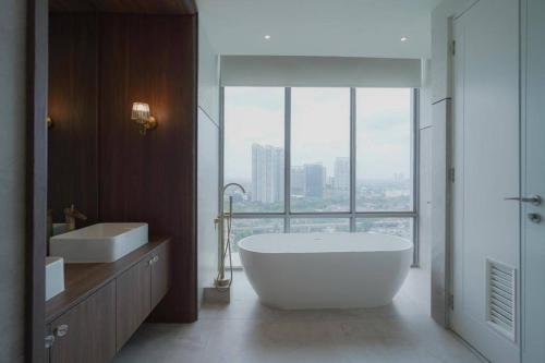 茉莉芬Sonar Paraiso: A Dreamy Apartment in Jakarta的一间带大浴缸和大窗户的浴室