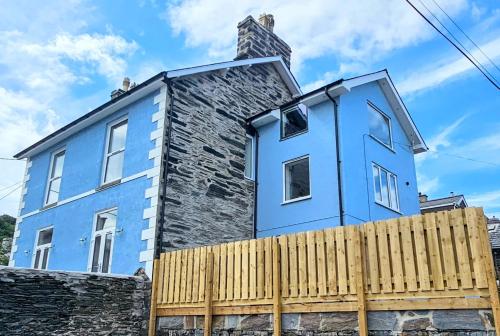 波特马多克Porthmadog, Sleeps 11, 5 Bedrooms, 5 Bathrooms, Mountain Views的木制围栏后面的蓝色房子