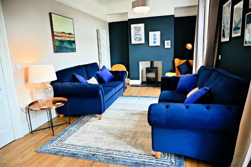 波特马多克Porthmadog, Sleeps 11, 5 Bedrooms, 5 Bathrooms, Mountain Views的客厅配有2张蓝色的沙发和1张桌子