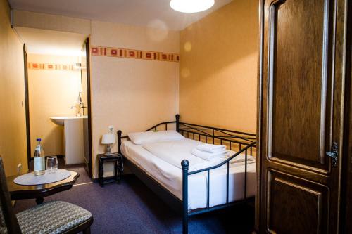 罗滕堡Hotel Schwarzer Adler的卧室配有1张床、1张桌子和1把椅子