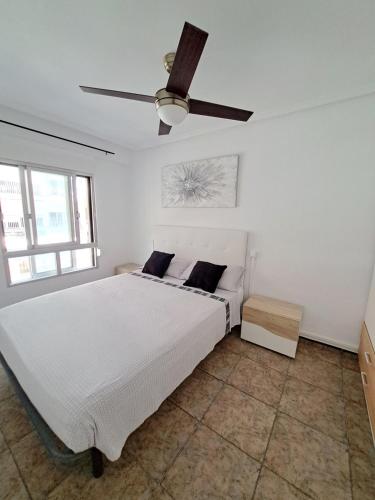 库列拉Apartamento 50mt Playa Cullera (San Antonio)的白色卧室配有床和吊扇
