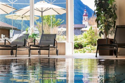 施图拜河谷新施蒂夫特斯图拜尔霍夫酒店的一座带椅子和遮阳伞的游泳池以及一座建筑