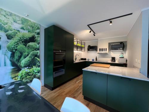霍尔滕Horten center的厨房配有绿色橱柜,墙上挂着一幅大画