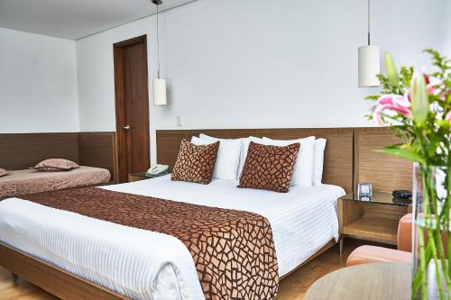 麦德林Hotel Poblado Alejandria的酒店客房设有一张大床和一张桌子。