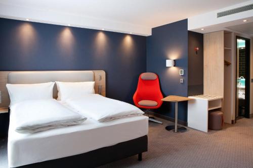 灵斯海姆Holiday Inn Express - Ringsheim, an IHG Hotel的一间卧室配有一张床和一张红色椅子