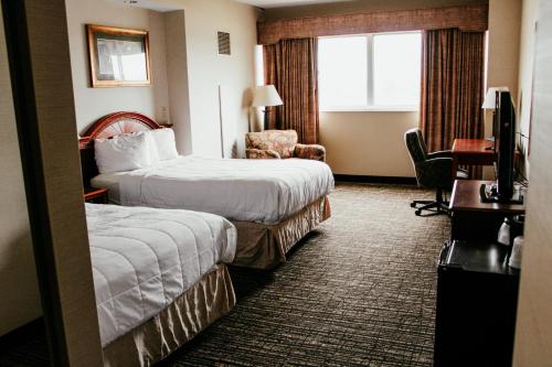 托皮卡Hotel Topeka at City Center的酒店客房,配有两张床和椅子