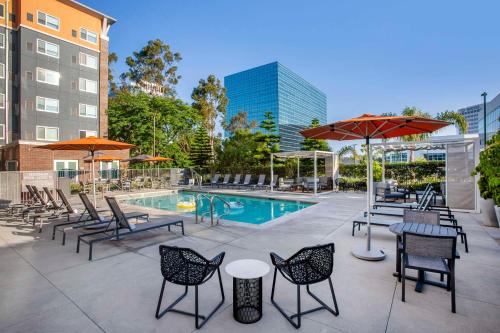 埃尔塞贡多Cambria Hotel LAX的一个带桌椅的庭院和一个游泳池