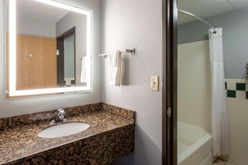 Silver BayBlack Beach Inn by GrandStay的浴室配有盥洗盆、镜子和浴缸
