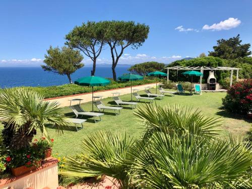 费拉约港Belvedere Residenza Mediterranea的连排带遮阳伞的草坪椅和海洋