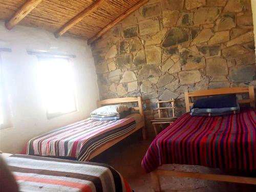 Estancia ChaunacaSamary -wasi maragua的一间卧室设有两张床和石墙
