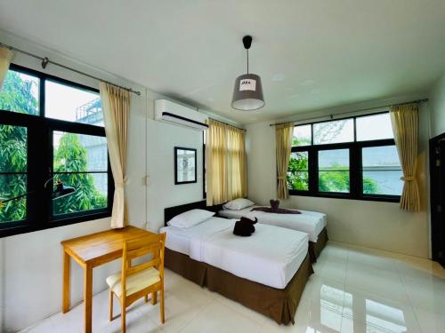 Bangkok Yaihome near MRT Tha Phra Villa sookkasem的一间卧室设有两张床、一张桌子和窗户。