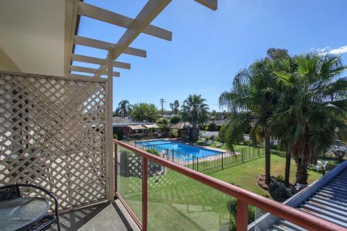 塔姆沃思Econo Lodge Gateway Tamworth的享有游泳池和棕榈树景致的阳台