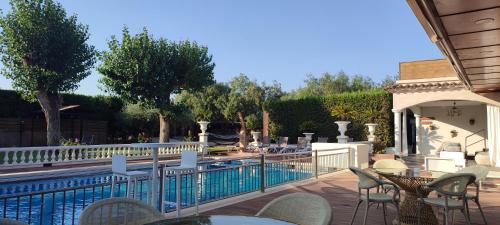 菲格拉斯Hotel & Restaurant Figueres Parc的游泳池旁带桌椅的天井