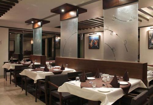 艾哈迈达巴德卡南酒店的餐厅设有桌椅和镜子