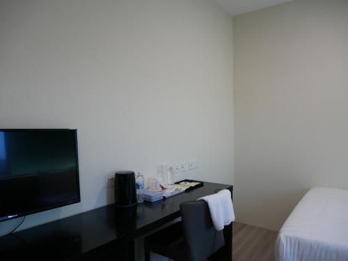 关丹Pantai Regal City Hotel的客房设有一张床、一张书桌和电视