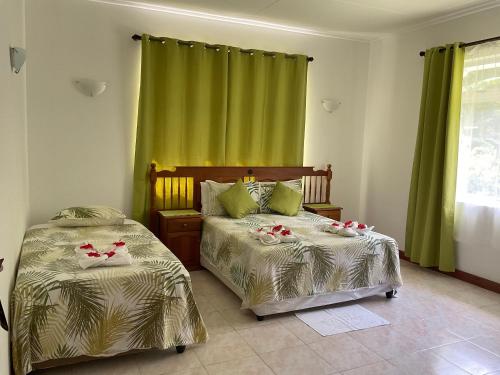 昂斯拉齐奥莱富安湾旅馆的卧室内的两张床,配有绿色窗帘