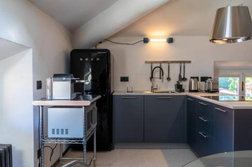 梅纳焦Casa Cometa Designer Attic Menaggio的厨房配有蓝色橱柜和黑色冰箱。