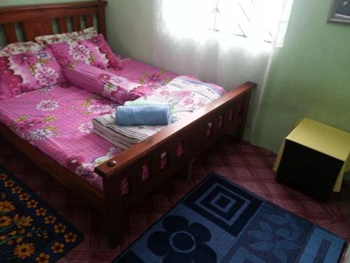 小笨珍Homestay Sri Perhentian Pontian的一间卧室配有一张带粉色床单的床和一扇窗户。