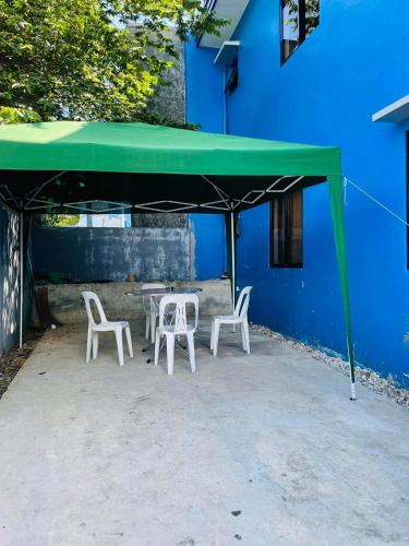 伊洛伊洛Marc louie estiaga home for rent的蓝色建筑旁边的绿色天篷下面的桌椅