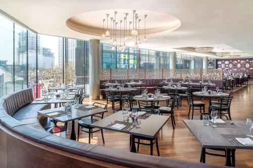 伦敦伦敦希尔顿温布利酒店的餐厅设有桌椅和窗户。