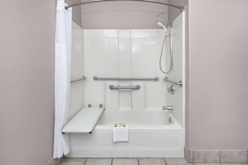 新布朗费尔斯Super 8 by Wyndham New Braunfels I-35的带淋浴的浴室配有白色浴缸。