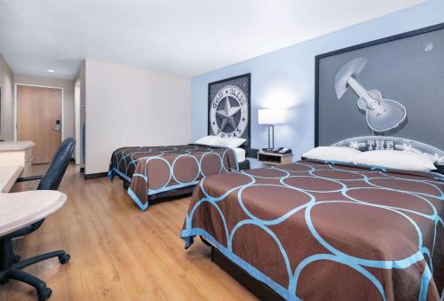 新布朗费尔斯Super 8 by Wyndham New Braunfels I-35的酒店客房带两张床和一张桌子以及椅子。