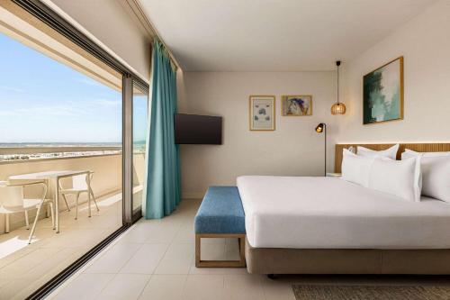 阿尔沃尔Wyndham Residences Alvor Beach的一间卧室配有一张床,阳台配有桌子