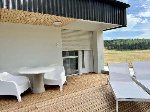 芒德Domaine de Mende Brenoux Suites & SPA的庭院配有白色的桌子和白色的椅子